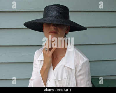 Modell weibliche Frau im breiten umrandeten schwarzen Hut mit weißer Bluse, ein direkter Blick in Kamera Mode Hände Stockfoto