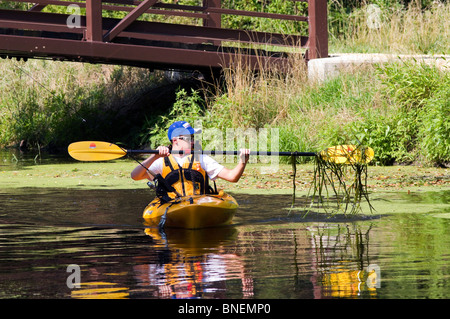 Eine kaukasische junge in einem Kajak mit Schwimmweste und Fanggeräte. Stockfoto