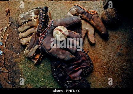 Verwittert, getragen von antiken 1950er Jahre Ära Baseball Handschuhe sammeln Staub in einem alten Bauernhaus auf der Mitte amerikanischen Prärien von Oklahoma Stockfoto