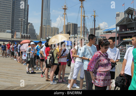 An einem heißen Tag im Juli Touristen Line-up in der South Street Seaport, auf einer Bootsfahrt rund um den Hafen von New York zu gehen. Stockfoto