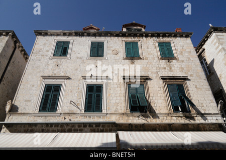 Grüne Fensterläden in den oberen Stockwerken eines alten Hauses über Laden an der wichtigsten Straße Placa Stradun alte Stadt von Dubrovnik in Kroatien Stockfoto