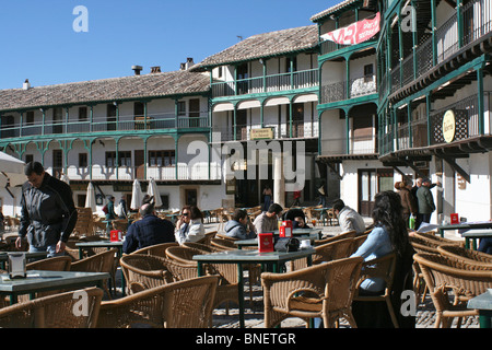 Sechzehnten Jahrhundert grüne Arkaden Gebäude rund um die Plaza Mayor in Chinchon mit Café-Tischen und Korbsessel Stockfoto