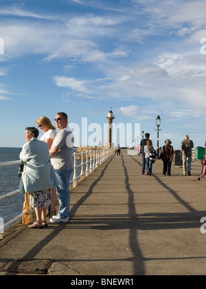 Menschen genießen die Abendsonne auf Whitby West pier Stockfoto