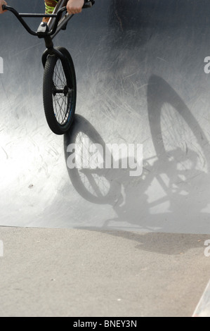 Ein Schatten eines BMX Stunt Bike auf eine Metallrampe in einem Skatepark Stockfoto