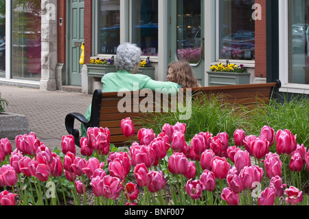 Eine Großmutter und Enkelin sitzen auf einer Bank in der Stadtstraße, Rückansicht, Bilder, Verkauf auf Alamy Michigan MI horizontal in USA US hochauflösend Stockfoto
