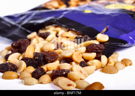 Gemischte Erdnüsse und Rosinen verschütten aus der Tasche. Isoliert. Stockfoto