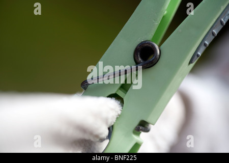 Naheinstellung Bild von einem grünen Kunststoff Wäscheklammer mit weißer Wäsche auf einer Wäscheleine Stockfoto
