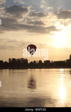 Heißluftballon fliegen über die Stadt Les Rosiers Sur Loire kurz nach Sonnenaufgang mit der Loire in den Vordergrund-Frankreich Stockfoto