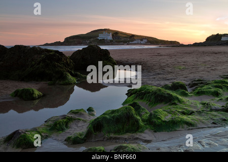 Bigbury-sur-mer und Burgh Island bei Sonnenuntergang, South Hams, Devon. Bei Ebbe zeigt Algen bedeckt Felsen am Strand. Stockfoto