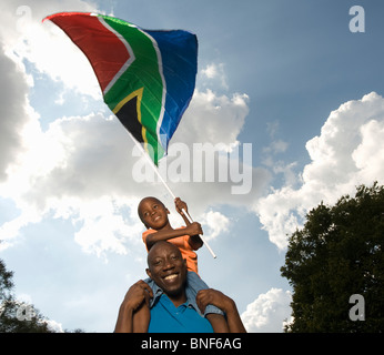 Vater mit Sohn (4-5) auf Schultern, winken südafrikanische Flagge, Johannesburg, Provinz Gauteng, Südafrika Stockfoto