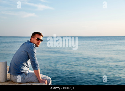 Mann sitzt auf dem Seeweg Stockfoto