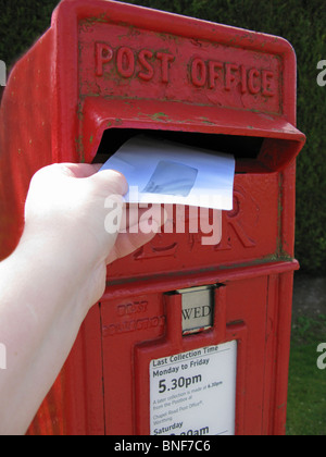 Frau einen Brief in einen roten Briefkasten buchen Stockfoto