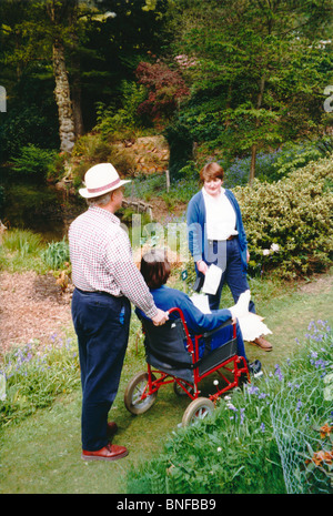 Frau mit einem Gipsverband am Bein im Rollstuhl besuchen Gärten in Surrey Stockfoto