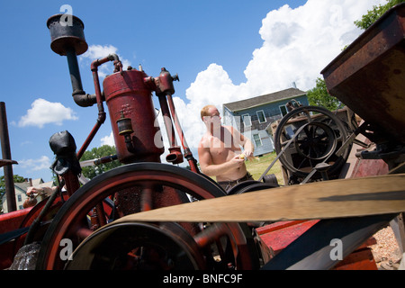 Mann einen Mais schälen Maschine bei einem antiken Gas und Dampf-Motor Show in Fort Hunter am Erie-Kanal in Betrieb. Stockfoto