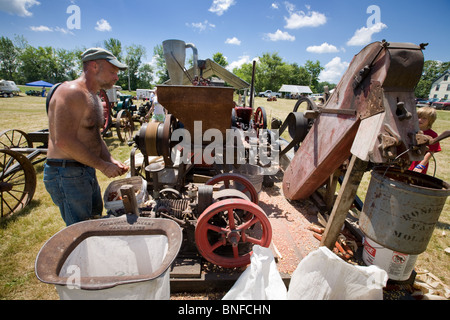 Mann einen Mais schälen Maschine bei einem antiken Gas und Dampf-Motor Show in Fort Hunter am Erie-Kanal in Betrieb. Stockfoto