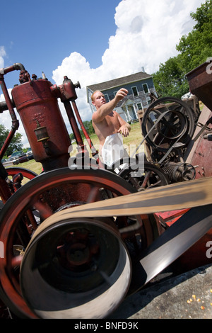 Mann einen Mais schälen Maschine bei einem antiken Gas und Dampf-Motor Show in Fort Hunter am Erie-Kanal in Betrieb. Stockfoto