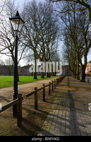 Einer von Bäumen gesäumten öffentlichen Stadtplatz mit einer Allee von blattlosen Bäume gehen in der Entfernung und einer Reihe von altmodisch, Lampe-posts. Stockfoto