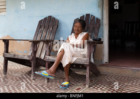 Eine Dame sitzt auf ihrer Veranda beobachten die Welt von Cayo Granma, Insel vor Santiago De Cuba Stockfoto