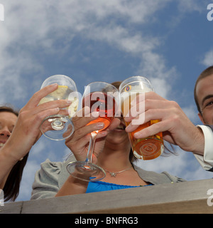 Drei Gäste ihre Getränke Gläser zusammen bei einer Hochzeitsfeier, UK Klirren Stockfoto