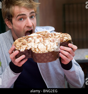 junger Mann Essen ein italienischer Osterkuchen in Gestalt einer Taube Stockfoto