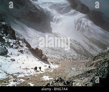 Porters kommen die letzten Hänge hinauf zum Pass im Lapsang-La mit Gletscher unterhalb der Kangchenjunga Region Osten Nepals Stockfoto