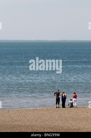 Vier Leute, am Strand bei Ebbe in Whitstable, Kent. Foto von Gordon Scammell Stockfoto