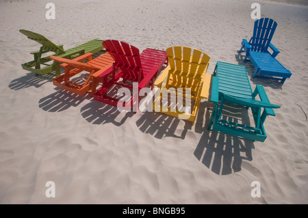 Eine Reihe von bunten Adirondack Sonnenliegen am Strand. Stockfoto