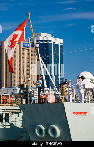 Kanadischen Segler erhöhen die Maple Leaf Fähnrich auf dem Achterdeck der Zerstörer HMCS ATHABASKAN während der 2010 Fleet Review. Stockfoto