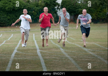 Wettbewerbsfähige Väter Sprint für die Linie in der Eltern-Rennen am Ende von einem traditionellen Ende der Begriff Schulsporttag Stockfoto