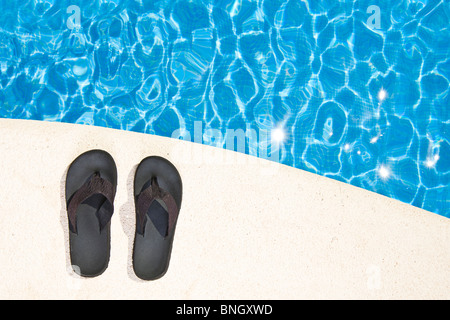 Schuss von einem Paar von Flip Flops neben dem Pool Stockfoto