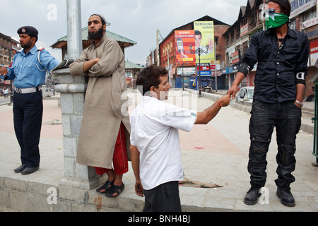 Straßenszene, ein Polizist und Einheimische stehen im Lal Chowk Teil zentralem Srinagar, Jammu und Kaschmir, Indien. Stockfoto