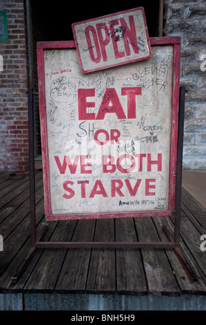 Ein lustiges Schild mit der Aufschrift "Essen oder wir beide Verhungern' außerhalb von Taylor Lebensmittelgeschäft Wels Restaurant in Taylor, Mississippi. Stockfoto