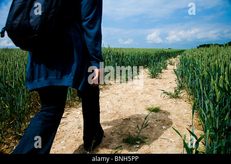 Frau zu Fuß auf einem öffentlichen Wanderweg durch ein Weizenfeld in Kent Stockfoto