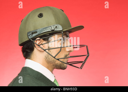 Geschäftsmann mit einem Cricket-Helm Stockfoto