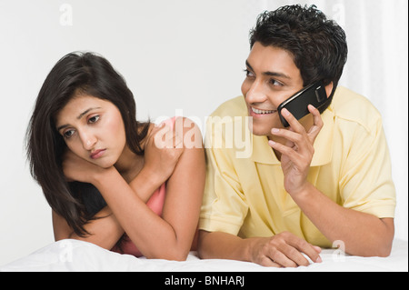 Mann mit einer Frau, die traurig neben ihm auf einem Mobiltelefon sprechen Stockfoto