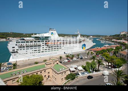 Ein riesiges Kreuzfahrtschiff im Hafen von Mahon auf der spanischen Insel Menorca Verzwergung der Kai Gebäude angedockt Stockfoto