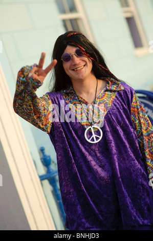 Ein Mann mit Peace-Zeichen als Hippie verkleidet, für eine 70er Jahre Dekade unter dem Motto Geburtstagsparty, UK Stockfoto