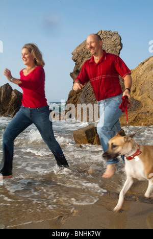 Paar jogging am Strand mit Hund Stockfoto