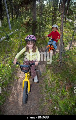 Kinder Fahrrad durch Wald fahren. Stockfoto