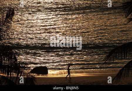 Silhouette der junge Frau in Thailand zu Fuß am Strand in der Abenddämmerung Stockfoto