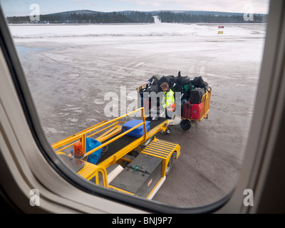 Ein Flughafenmitarbeiter lädt die Passagiere Fälle in ein Flugzeug am Flughafen Kiruna. Stockfoto