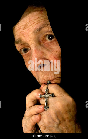 Alte Frauen tief im Gebet tragen einen schwarzen Schleier hält einen Rosenkranz Stockfoto