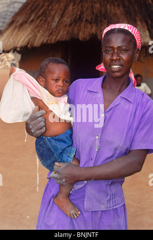 Afrikanerin Holding Baby im Arm vor Dorf Hütte in ländlichen Simbabwe Stockfoto