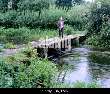 Frau stehend auf Kebles Brücke über den Fluss Leach zwischen Eastleach Turville und Eastleach Martin, in der Nähe von Lechlade, Glos. Stockfoto