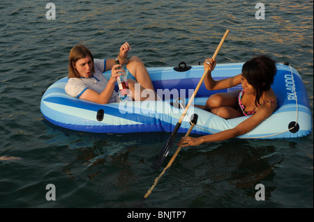 Zwei junge Menschen in ein Schlauchboot, trinken eine Flasche Wein, Aberystwyth Wales UK Stockfoto