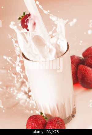 Gießen Milch spritzt aus Glas mit Erdbeeren Stockfoto