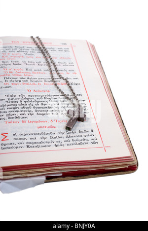 silbernes Kreuz in einer offenen alten Bibel mit Lederbezug isoliert auf weiss Stockfoto