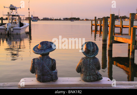 Kind-Statuen am Dock bei Sonnenuntergang, Silver Lake Harbor, Ocracoke Island, Cape Hatteras National Seashore, North Carolina, USA Stockfoto