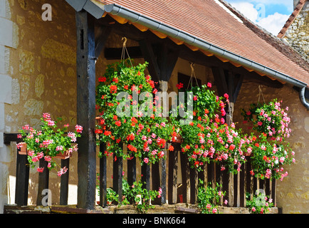 Hängende Körbe und Pflanzer auf Holzbalkon renoviertes Steinhaus - Frankreich. Stockfoto