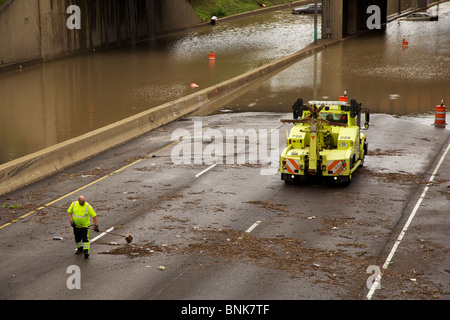 Autobahn Arbeitskraft löscht Trümmer Insterstate 290 nach einem schweren Hochwasser. Gestrandete Autos im Hintergrund. Stockfoto